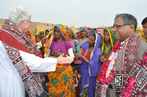 Columban Fr Robert McCulloch (left) speaks to rain-hit families after handing over ownership papers of the houses built by the St Elizabeth Hospital, Hyderabad, and the Catholic Church in Jherruck town.