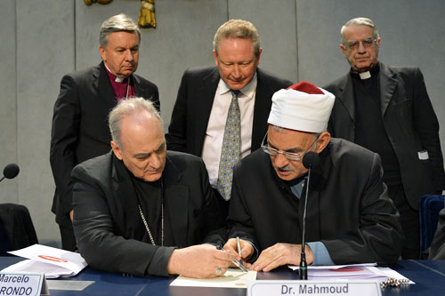 Catholic bishop and Chancellor of the Pontifical Academy of Sciences, Argentinian Marcelo Sanchez Sorondo (L) and Professor Mahmoud Azab (R), advisor of the Grand Imam of Al-Azhar University sign the  "Global Freedom Network"  agreement between representatives of Catholic church, the Anglican church and Sunni University Al-Azhar to fight against "modern forms of slavery and human trafficking," as Mining billionaire Andrew "Twiggy" Forrest (C), Anglican bishop, Sir David John Moxon (topL) and the director of the Holy See press office, Federico Lombardi (topR) look on, on March 17, 2014 at the Vatican. AFP PHOTO CREDIT: ANDREAS SOLARO