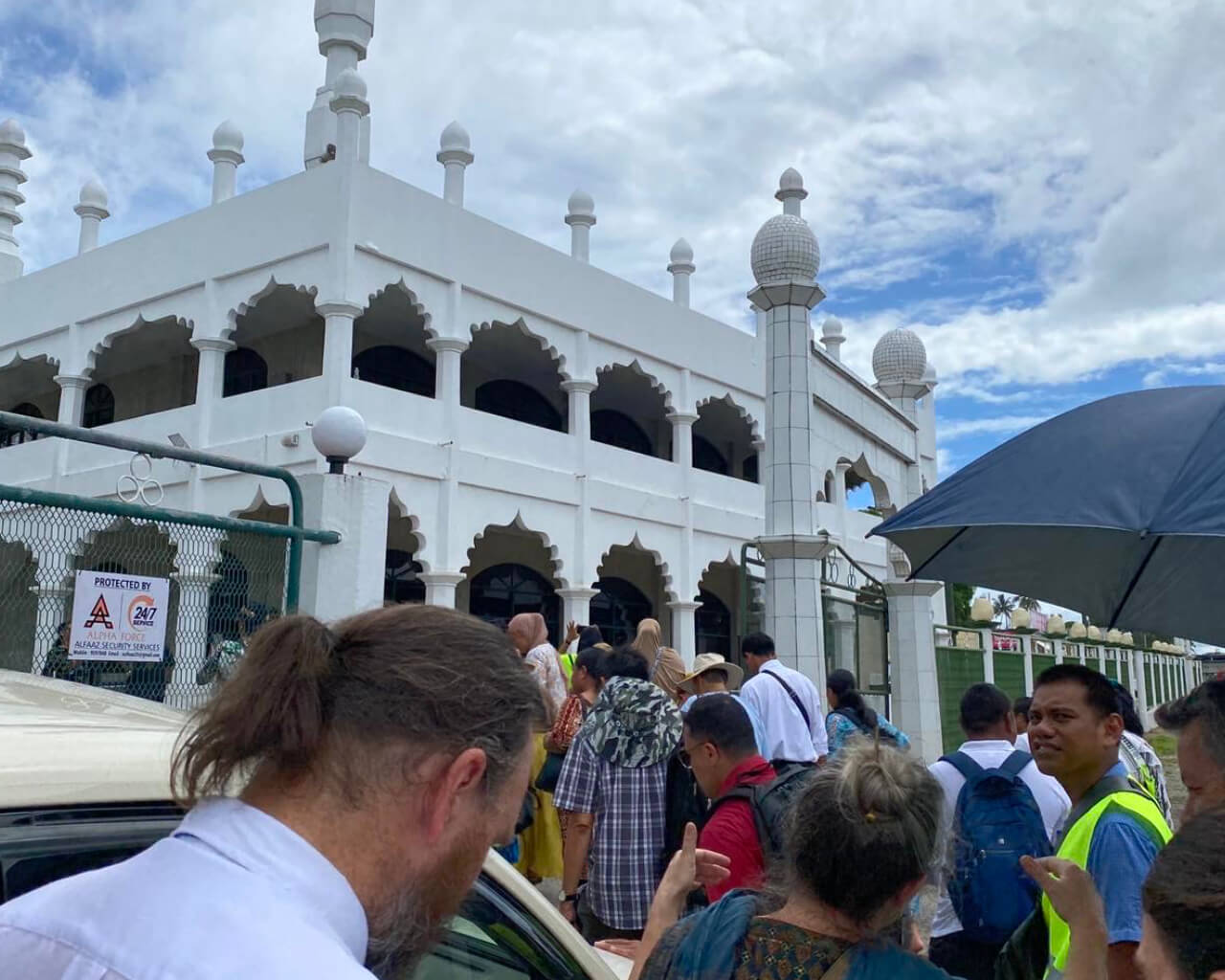 The pilgrims stand at the mosque’s doorstep, ready to enter and listen to their religious leaders’ words of wisdom.