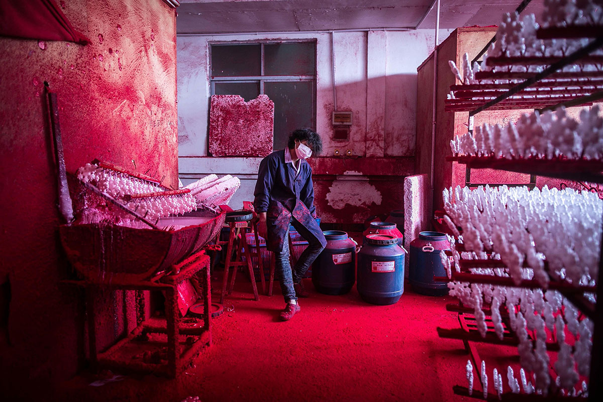 Chinese worker Wei wearing a face mask rests next to Christmas plastic snowflakes. Photo: Imaginechina Limited/Alamy